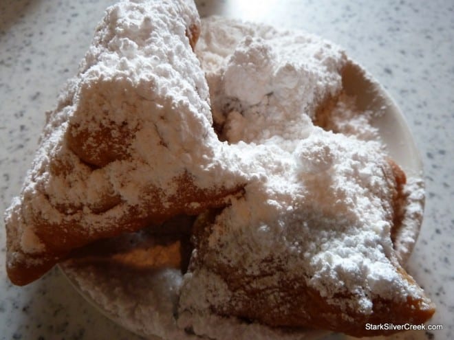 Three hot beignets covered in powdered sugar on a plate