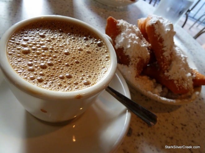 Cup of café au lait next to a plate of fresh beignets