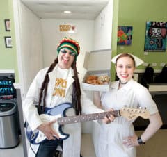 Jordan Zweigoron, chief psycho, and Dylan Syrett, nurse,  stand with guitar and donuts in front of the shop's new music studio, where customers can play the electric guitar.  (George Sakkestad/Campbell Reporter)