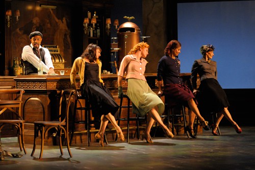 The Musician (Gregory Wallace) keeps the drinks coming while the women wait for their men to return from World War II (from left: Lorena Feijoo, Sara Hogrefe, Rachel Ticotin, Sabina Allemann). Photo by Kevin Berne.