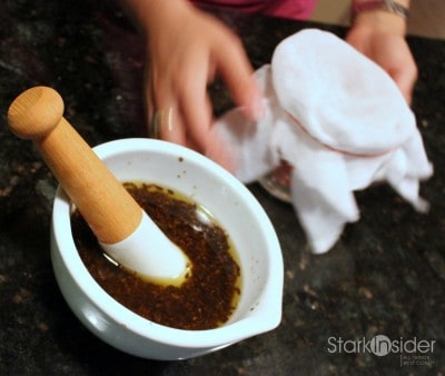 Creating the strainer using cheesecloth, a measuring cup and an elastic band. cold-pressed lavender oil in jojoba mortar