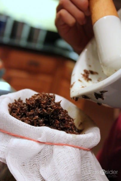 Pouring the lavender flowers and oil into a cheese cloth.