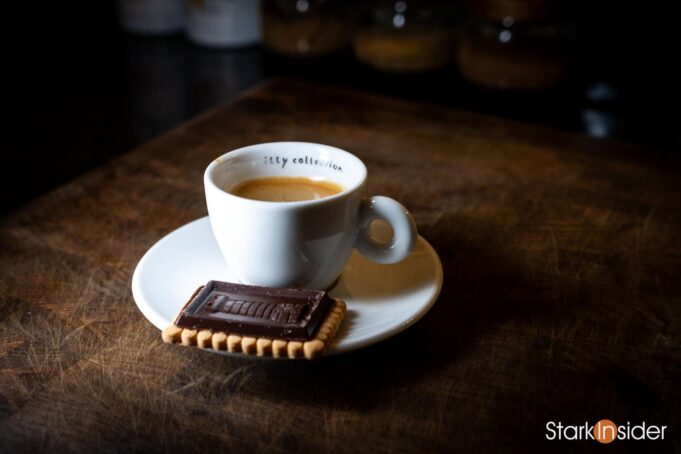 A rich espresso in a white Illy cup, served with a chocolate-topped cookie