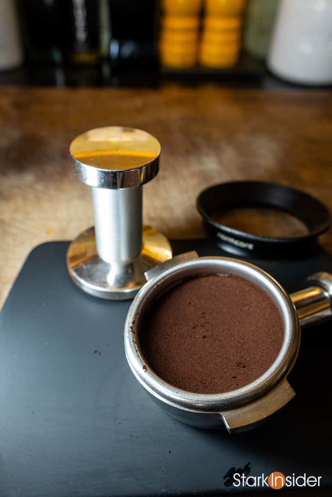 Close-up of tamped espresso puck in portafilter with dosing funnel and tamper