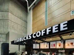 Starbucks coffee kiosk with illuminated signage and a “Line Starts Here” sign, representing launch of the Fall 2025 menu