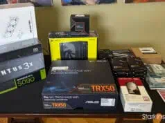 AI lab hardware parts laid out on table including RTX 5090 GPU, ASUS TRX50 motherboard, and Threadripper box.