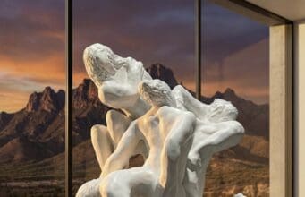 The Third Mind: Inviting Our AI Agents to Our Summit White sculptural tangle of human figures by Loni Stark in front of desert mountains at sunset, artwork for the Third Mind AI–human collaboration summit