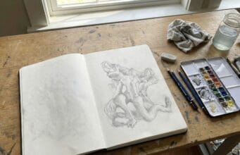 The Memento Problem: Notes on AI, Memory, and The Third Mind Summit Artist’s sketchbook open on a wooden desk, exploring creativity and human–AI collaboration ahead of the Third Mind AI Summit