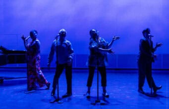 Theatre Bay Area Celebrates 50 Years of Arts Excellence Four performers stand at microphones on a stage bathed in dramatic blue lighting during a Theatre Bay Area production