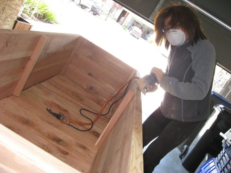 Loni Stark sanding a wooden planter box